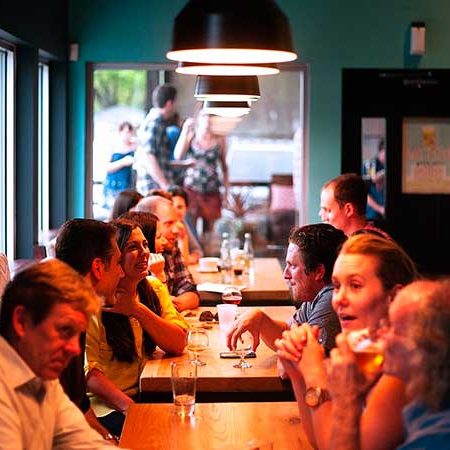 A line of tables at a restaurant, each filled with patrons enjoying drinks and conversation.