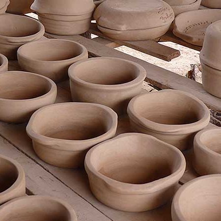 Rows of raw clay dishware ready to be cooked.